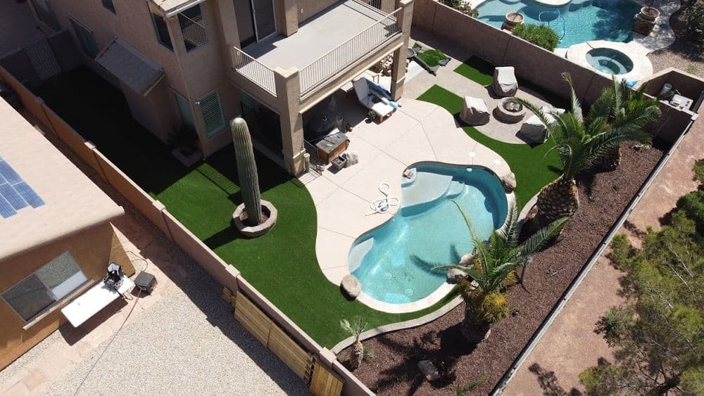 Aerial view of a backyard with a pool, lounge chairs, and landscaping features.